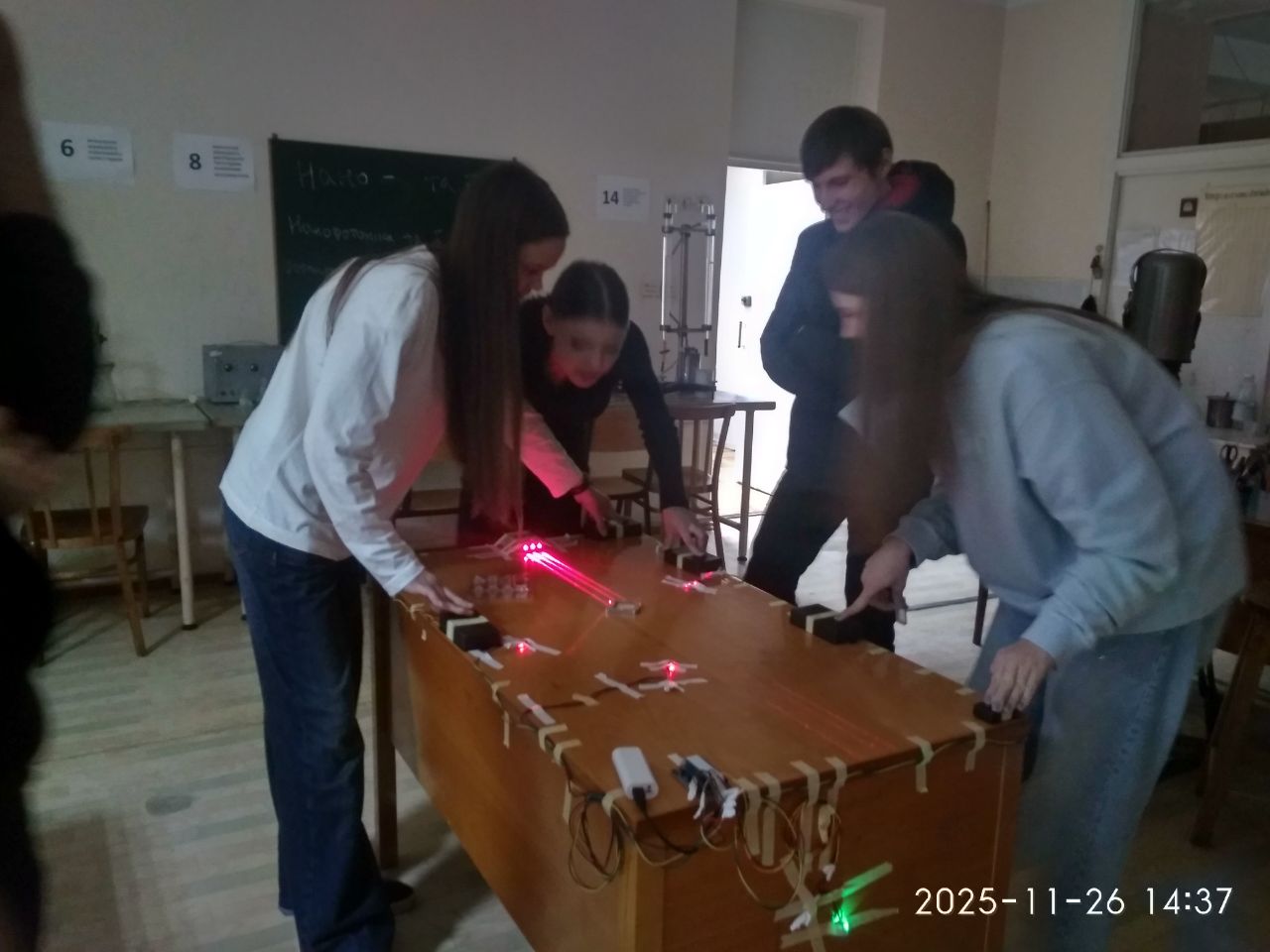 Школярі за оптичним столом, видно червоний лазерний промінь